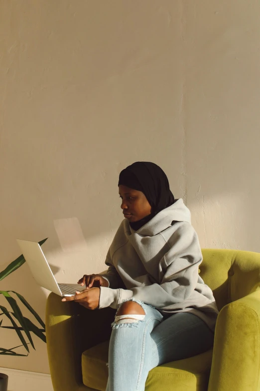 a woman sitting in a yellow chair while on a computer