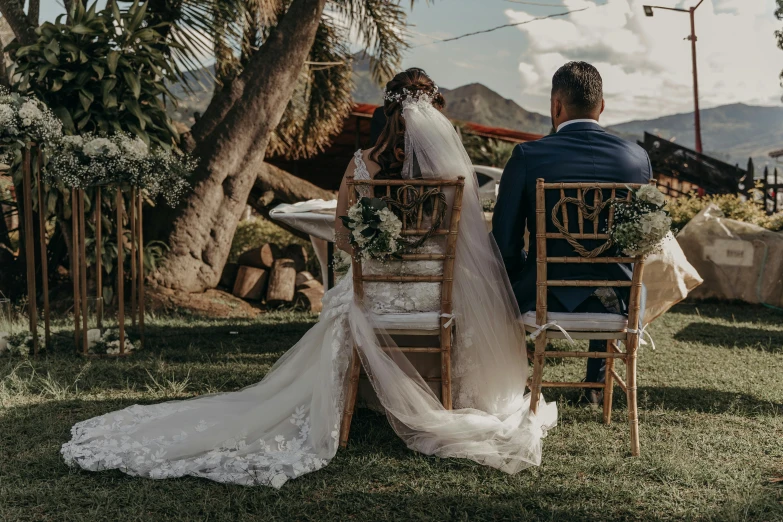 the bride and groom sit on their wedding day in the palm trees