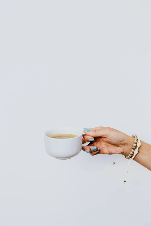 a woman's hand holding a cup of coffee