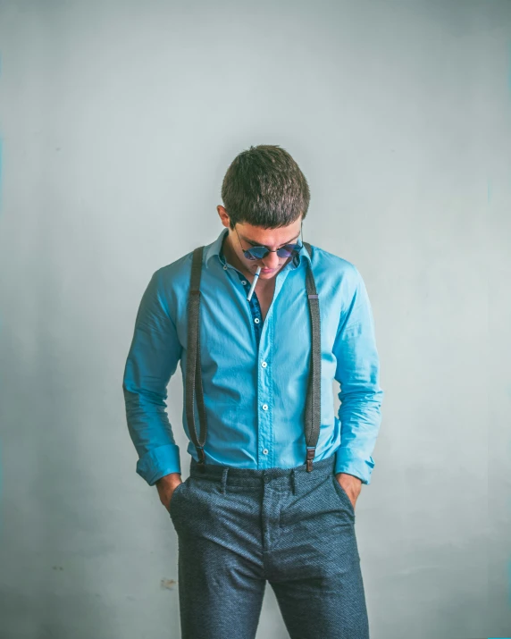 man in blue dress shirt and suspenders with grey background