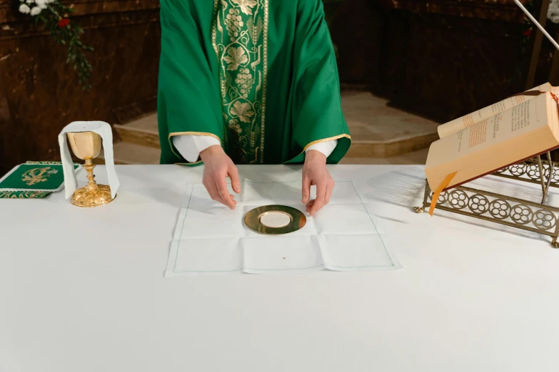 priest in green robe placing the cross on the paper