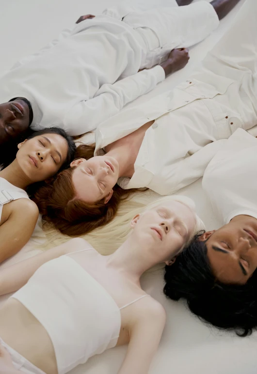 three people are lying on a white bed