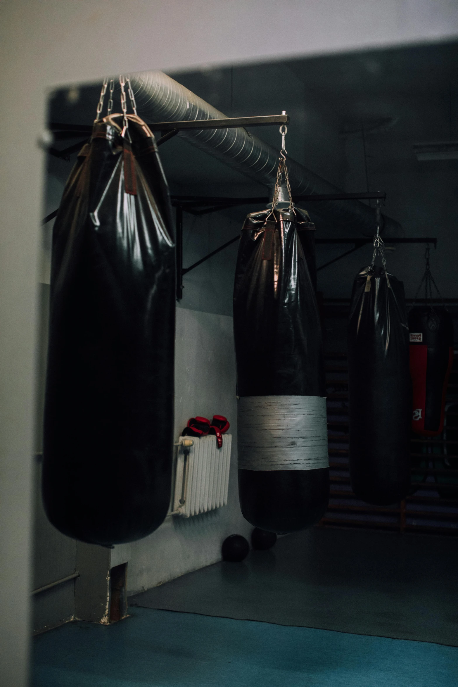 black boxing bag and gloves are hanging from a wall