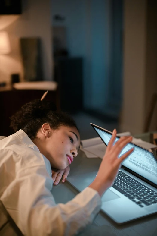 young woman laying down at desk looking at a tablet