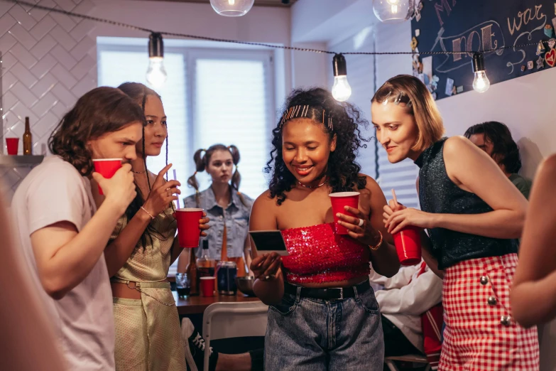 three girls talking in a kitchen with red cups