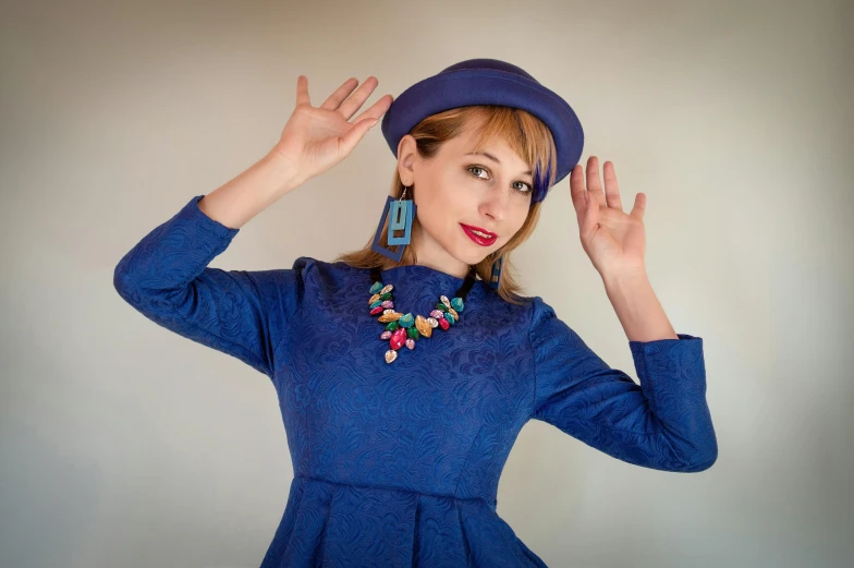 a woman with hands up and wearing blue is posing
