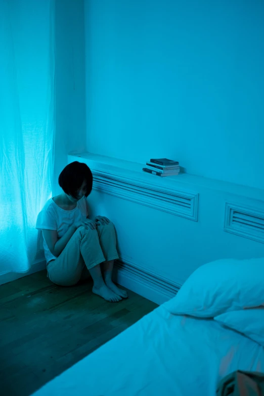 a woman sits in the dark looking at her cell phone