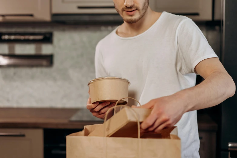 a man is opening up a brown paper bag and putting it in a paper bag