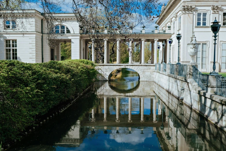 the reflection of a house on a canal in front of a bridge