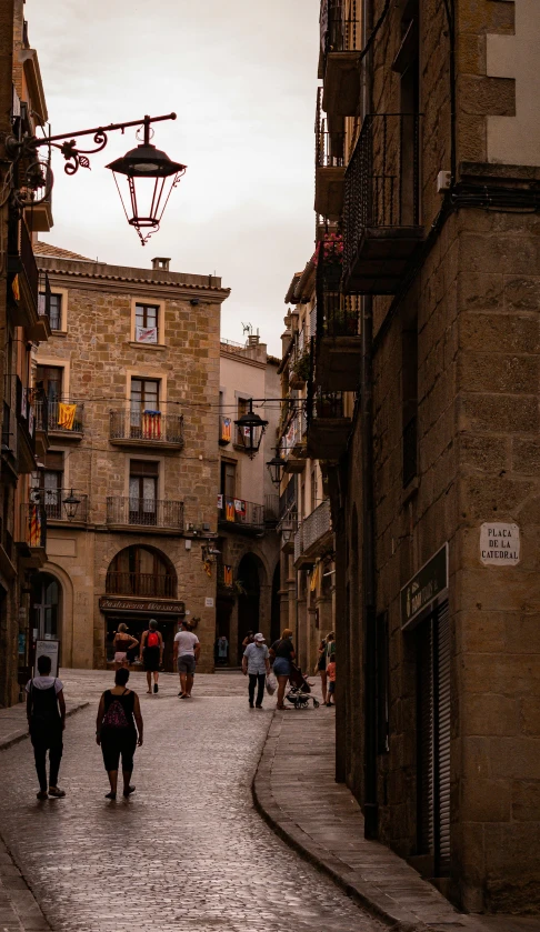 several people are walking down the stone walkway between the buildings