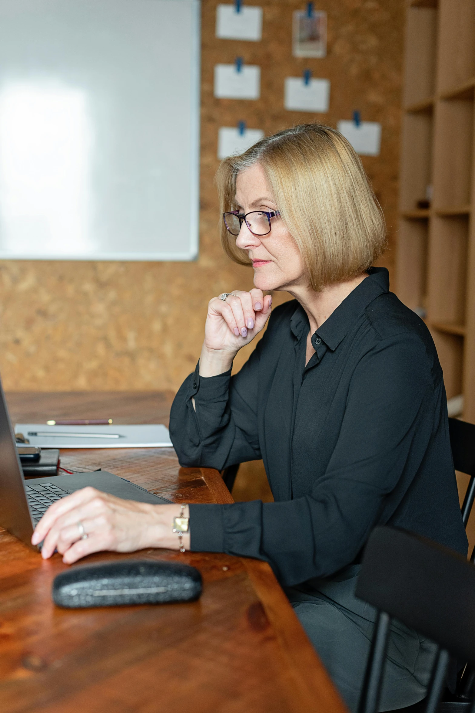 a woman is typing on her laptop while leaning up against the edge