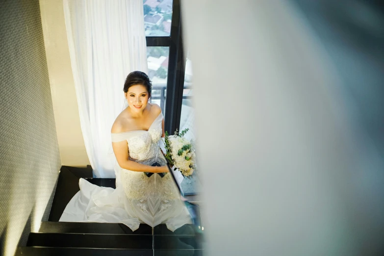 a bride sitting on the stairs wearing a white dress