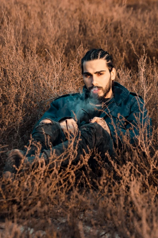 a man sitting in the middle of a field with his head resting on his hands