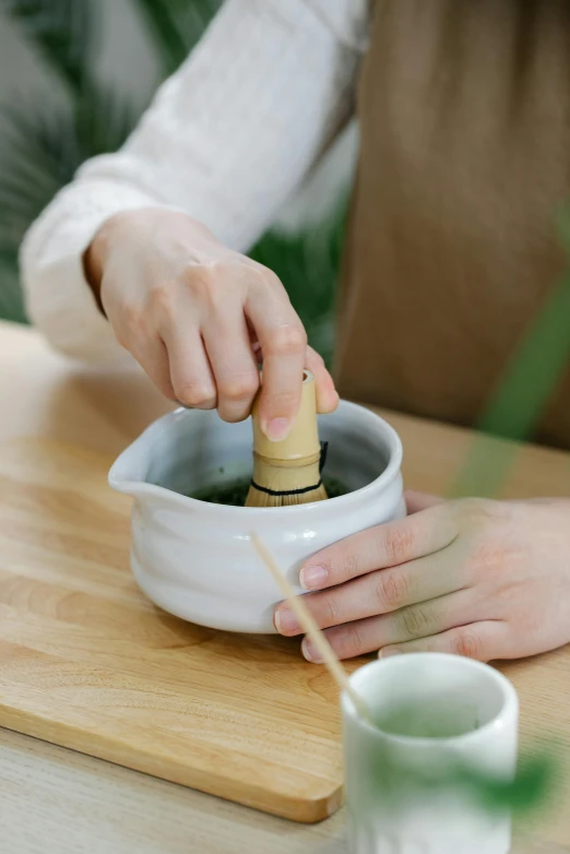 someone is putting an olive in a white ceramic bowl