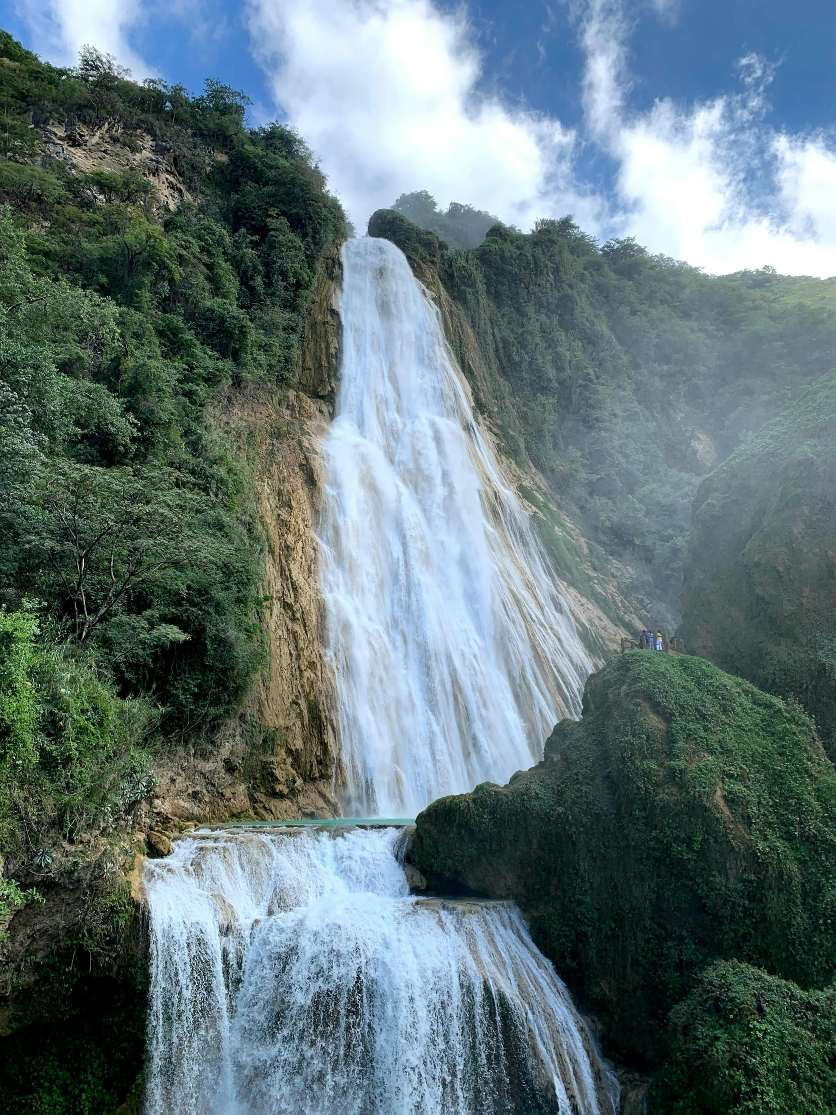 a waterfall with people below and water cascading