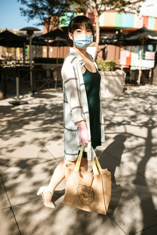 a woman in a face mask walks with a bag