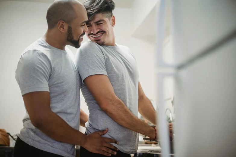 two men standing in a room together next to a refrigerator