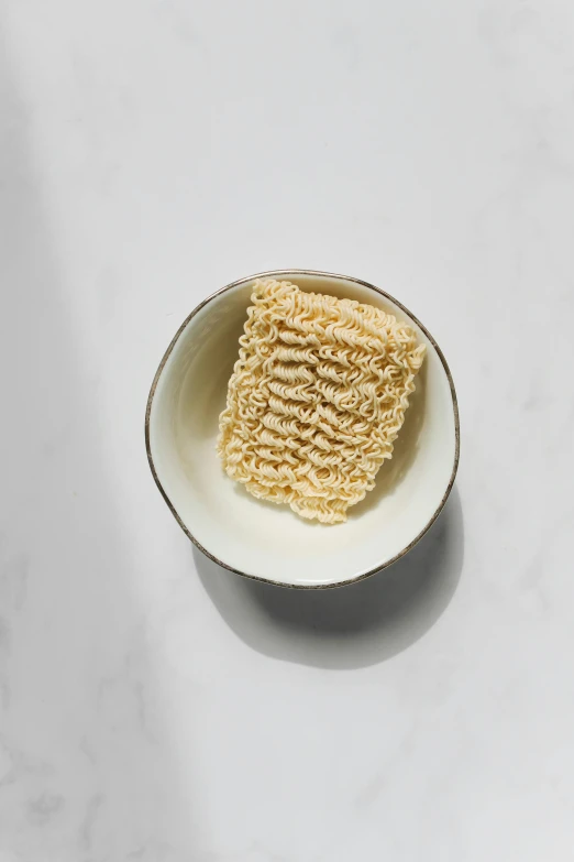 a small dish with some noodles inside on a white table