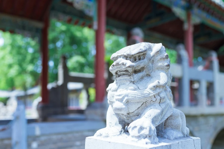 an old statue of a foo dog in front of a pavilion