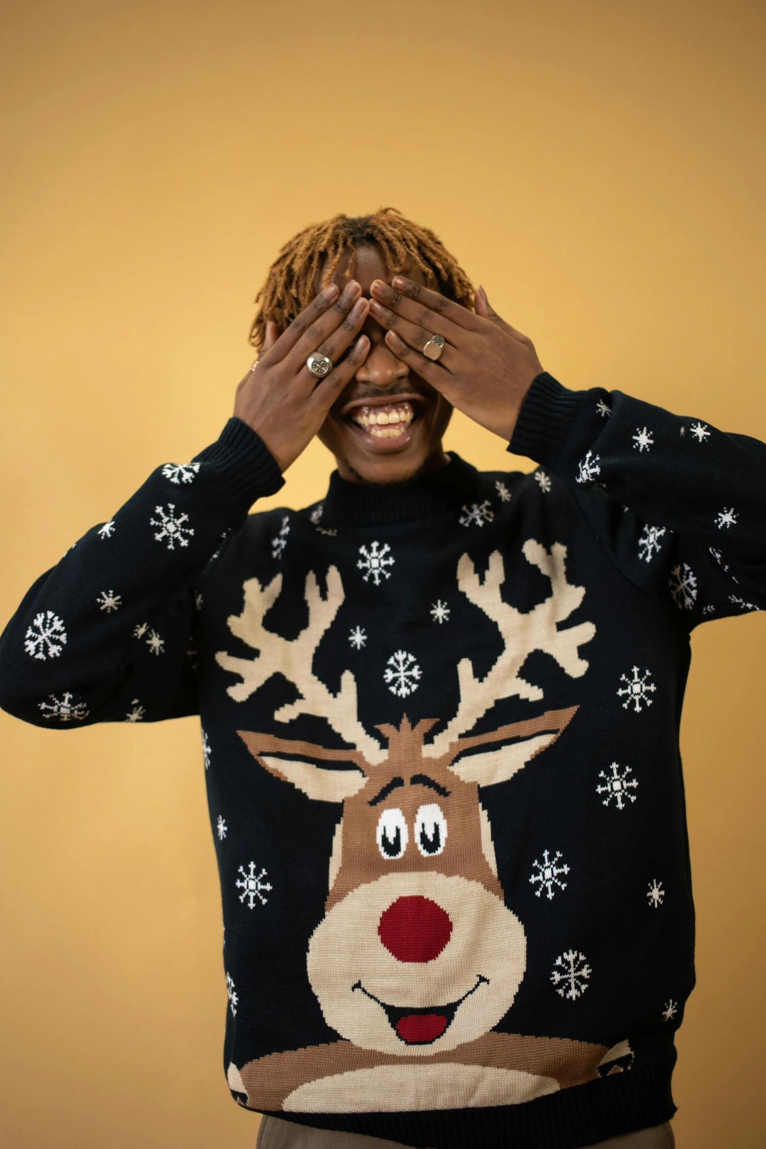 the young man in a reindeer sweater covers his eyes