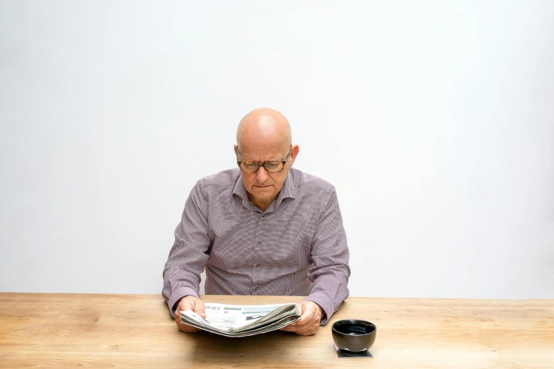 man reading an article on a table with a cup of coffee