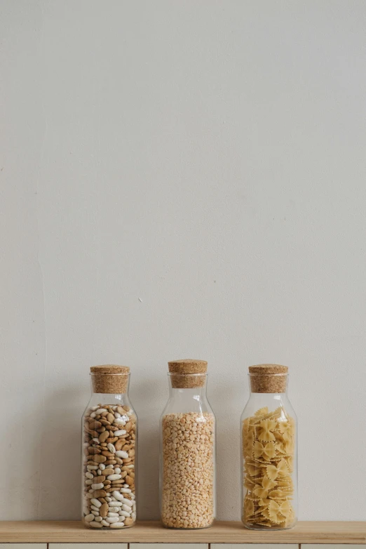 three glass jars filled with cereal on a shelf