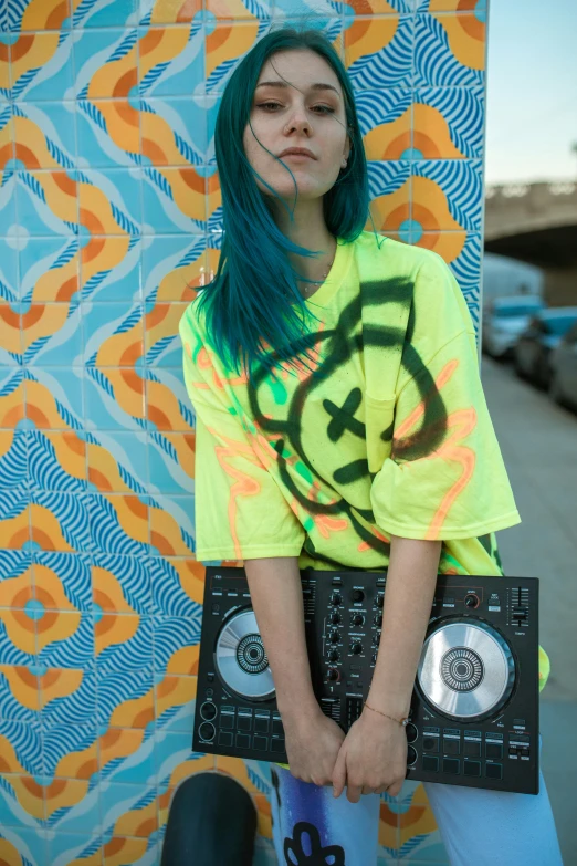 a woman standing by a wall holding onto two laptops