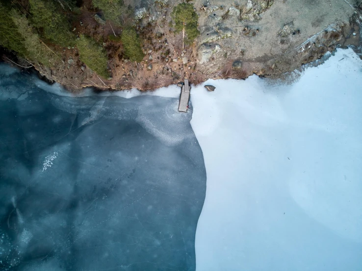 an aerial view of an icy lake with snow