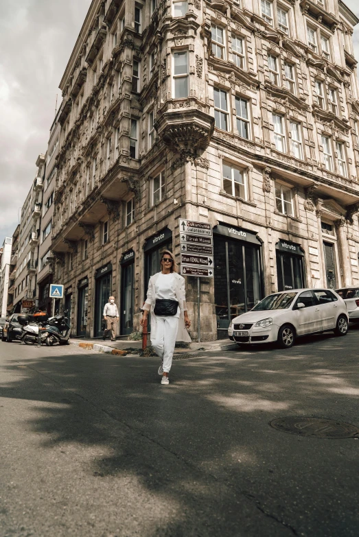 a woman walks down a city street past a tall building