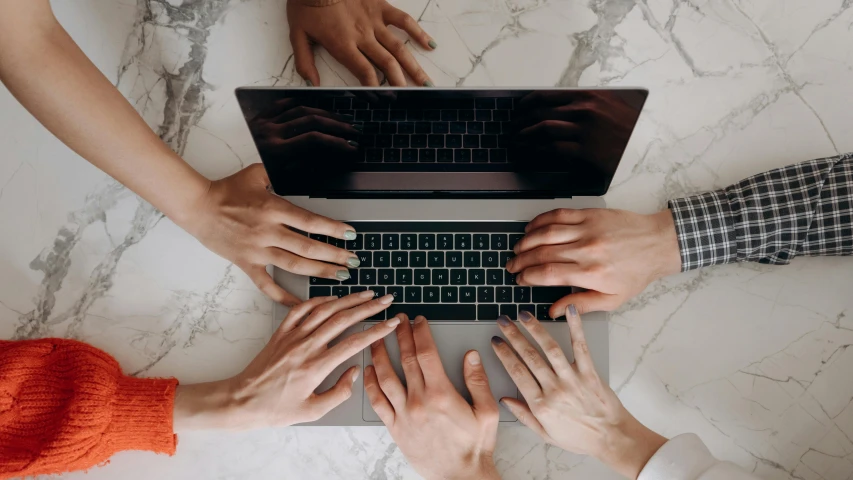 a group of people work on a laptop at a table