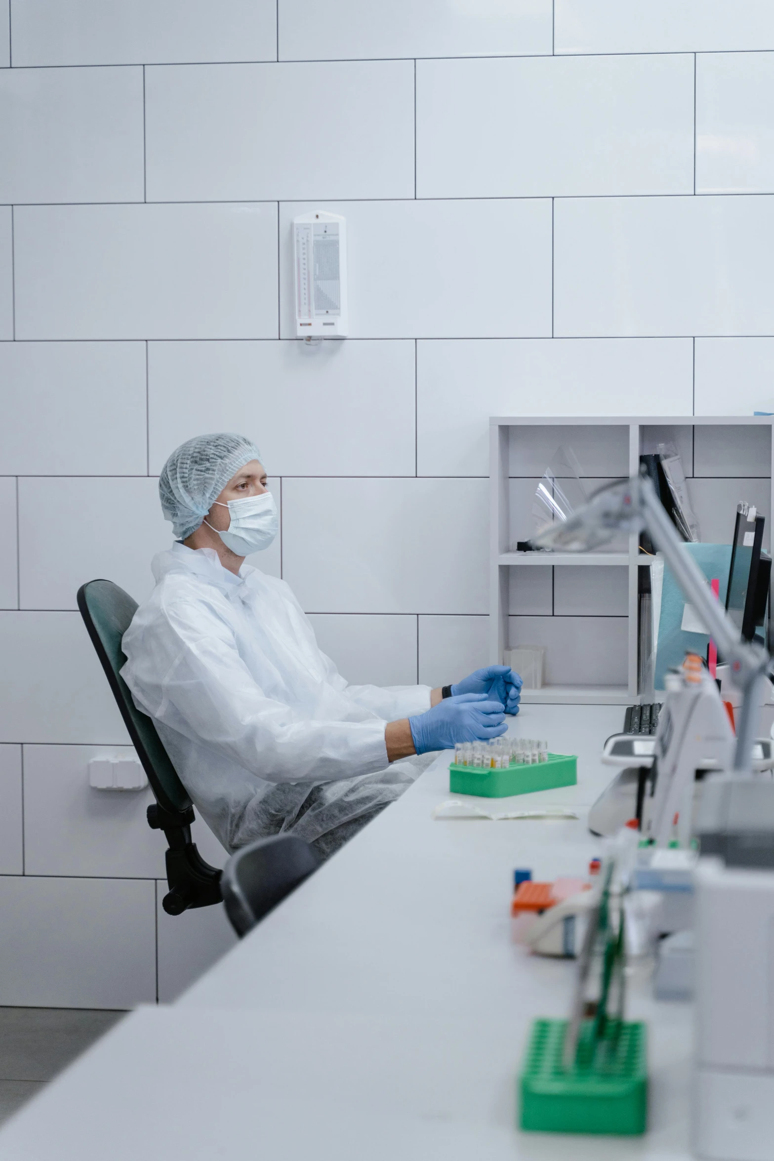 a man sits at a lab desk in white work wear