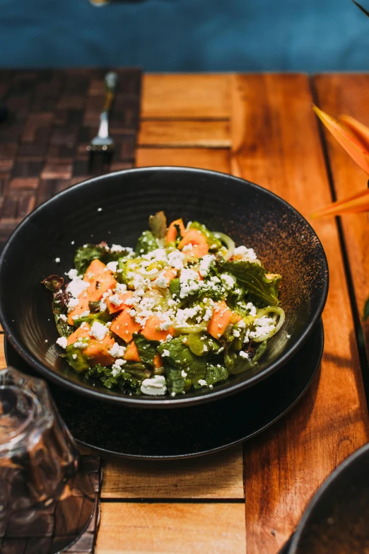 a bowl filled with vegetables on top of a wooden table