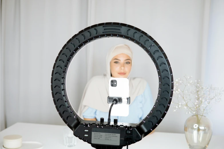 a woman in hijab standing next to a camera