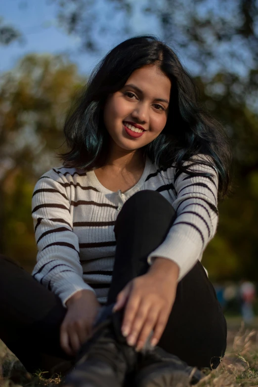 an indian girl wearing striped shirt and black pants is posing for a pograph