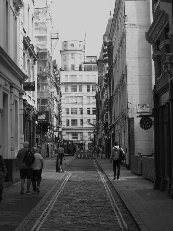 pedestrians walk down the cobblestone street in a city