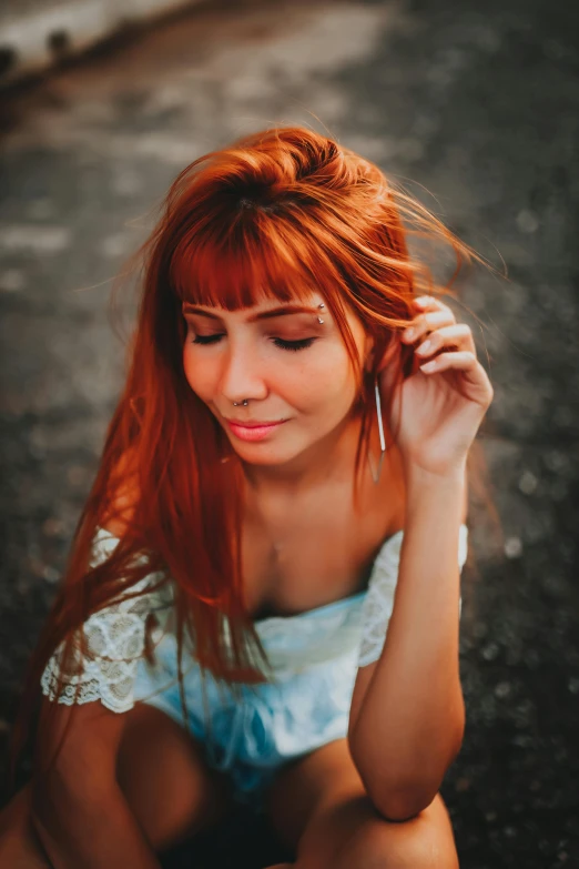 a girl is sitting on the ground with her hair up