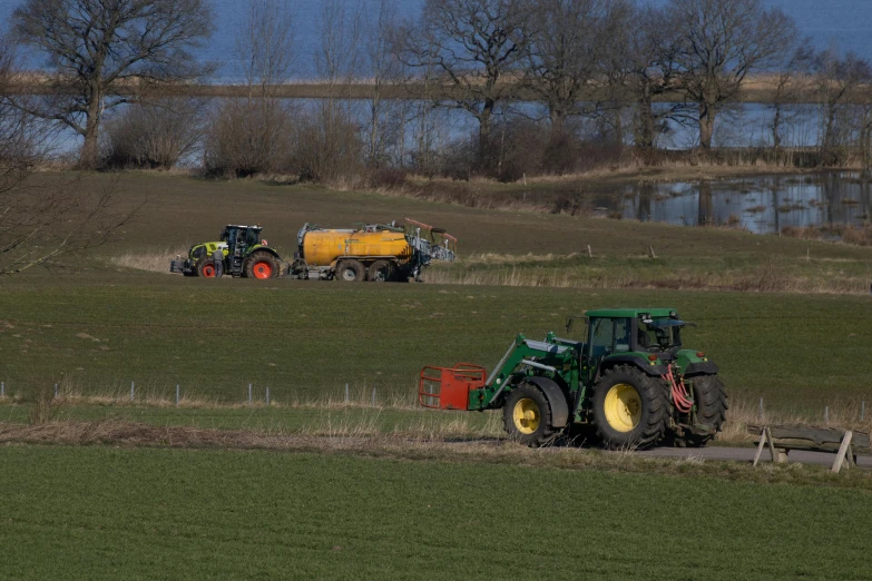 two tractor parked in a field by some water