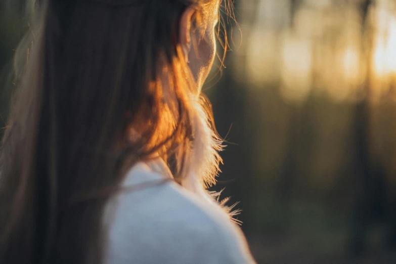 a woman with long hair walking in the woods