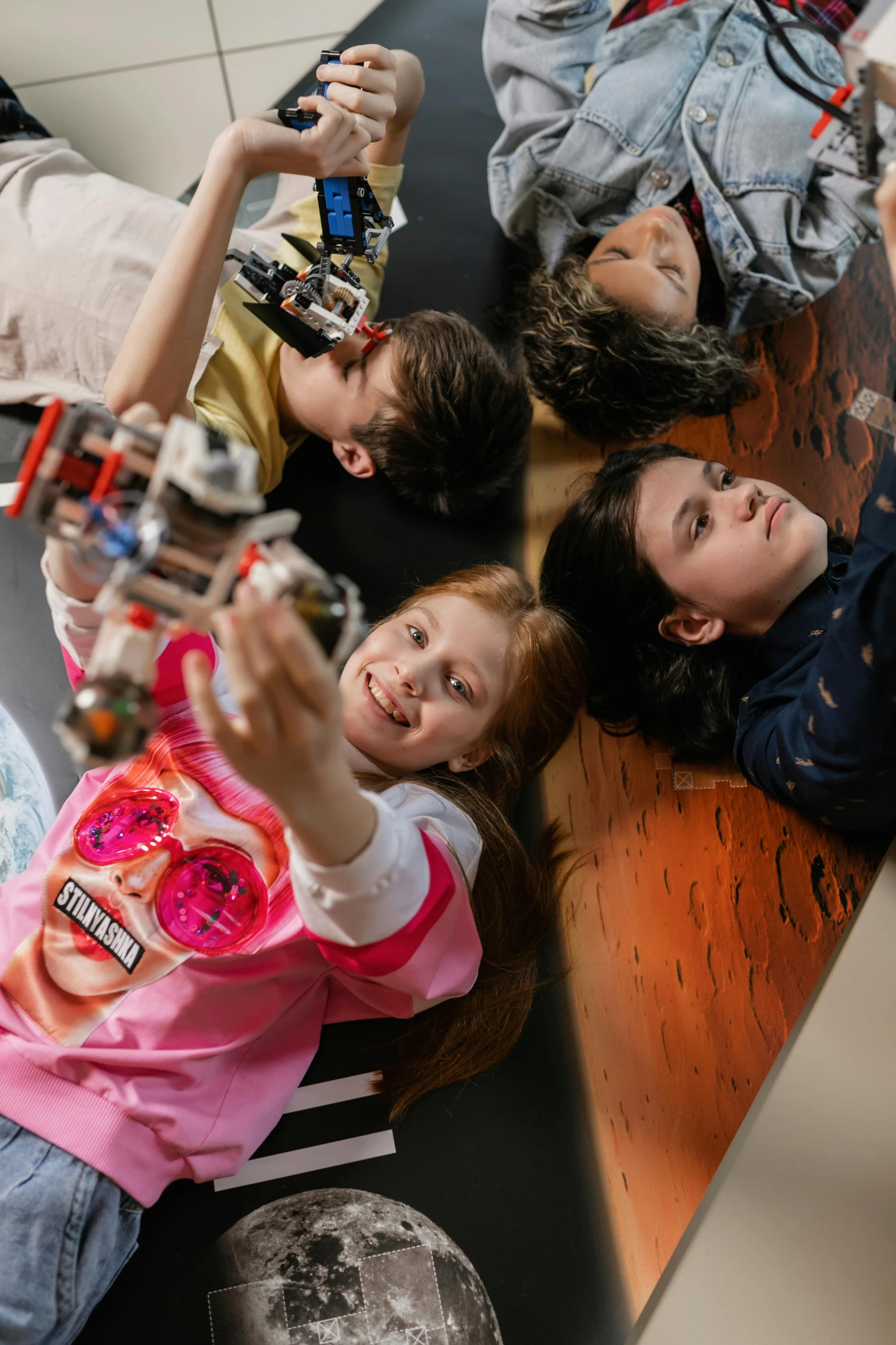 young children taking pictures of themselves while sitting on the ground