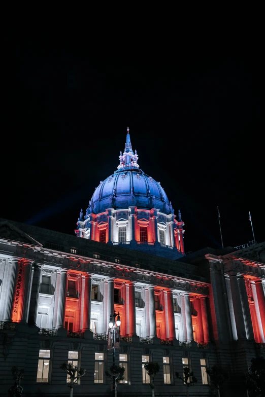 a dome is lit up at night, and red light shines from the windows