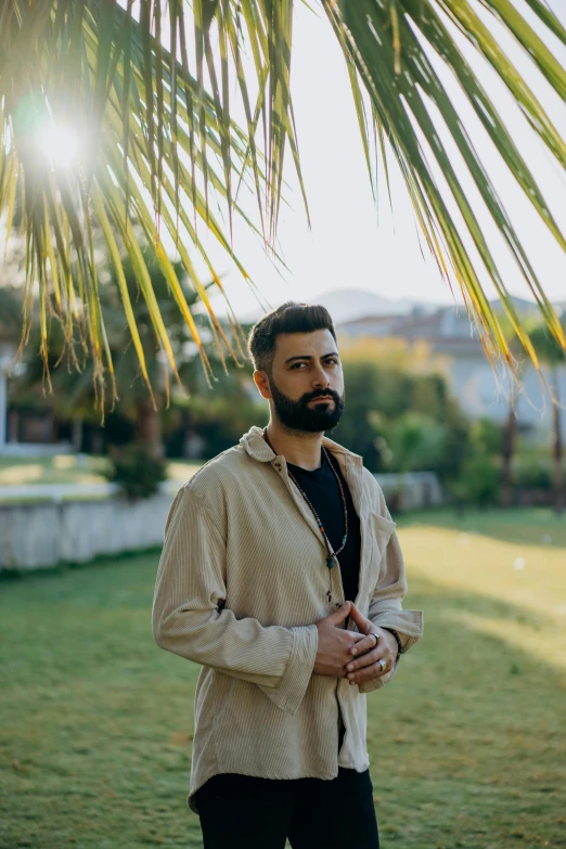 a man is standing under a palm tree