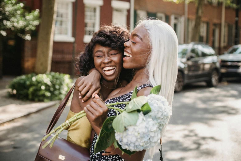 two women hugging each other and holding a bouquet