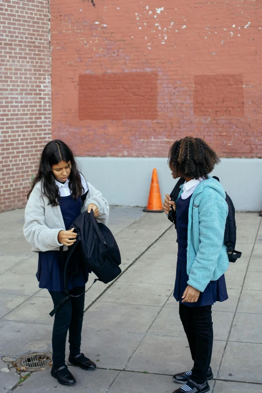 two girls standing next to each other, talking on the street