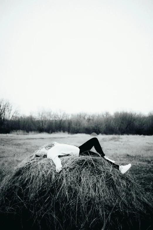 the woman is laying on the hay in the field