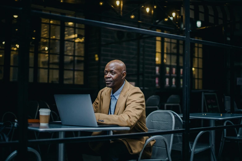 a man in a suit sitting at a table on his laptop