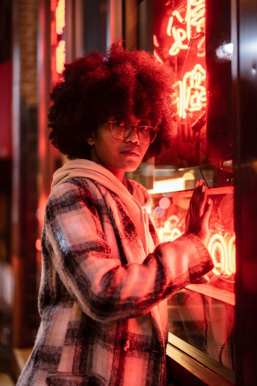 woman standing in front of a red light with afro hair and glasses