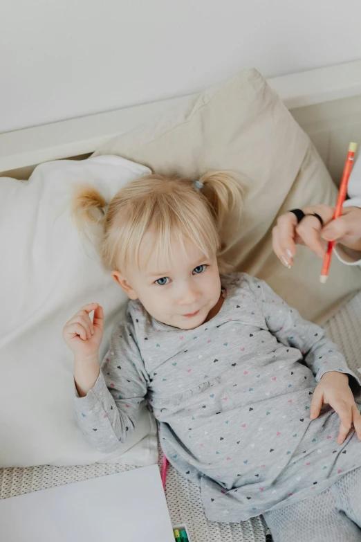 a  lying in bed with a crayon on her leg