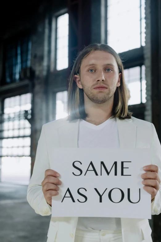 a man holding a sign that reads same as you