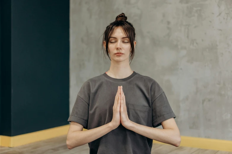 a woman meditating while wearing a gray shirt