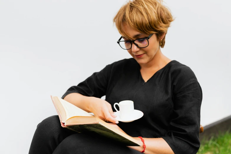 a woman sitting on the ground reading a book